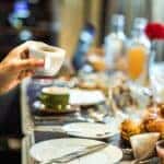 Person holding a cup of espresso over a dinner table