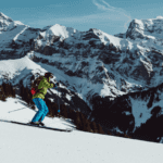 person skiing downhill in green jacket