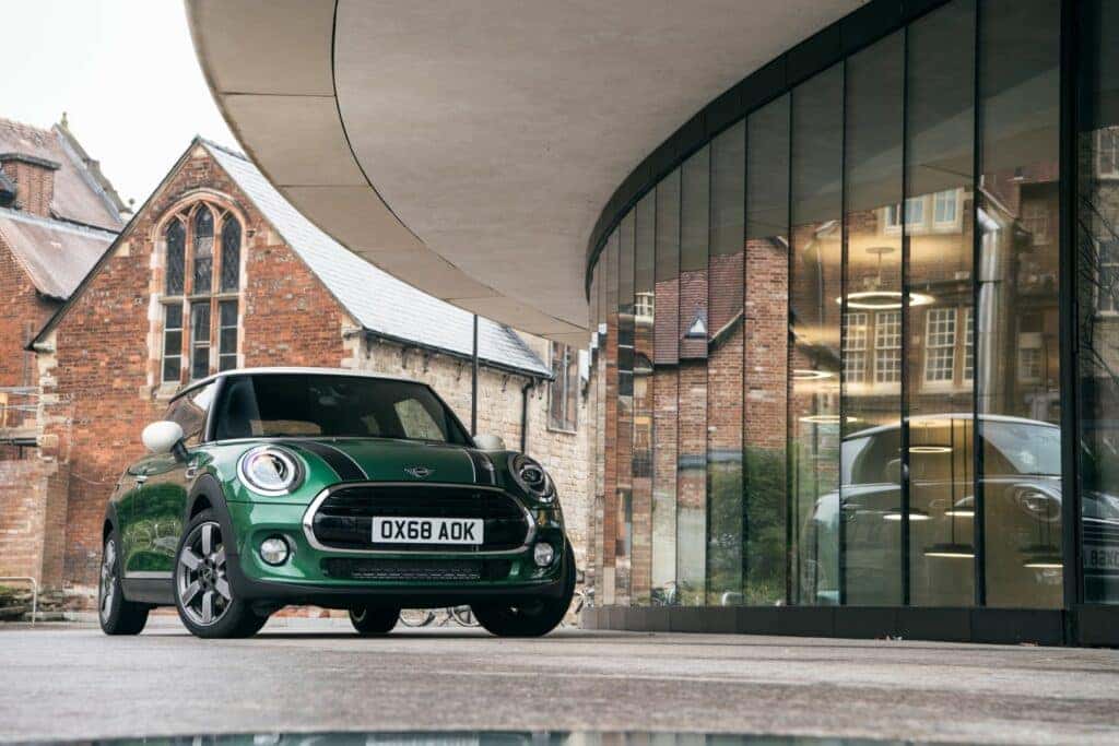 A forest green 2021 MINI Cooper parked near a building