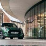 A forest green 2021 MINI Cooper parked near a building