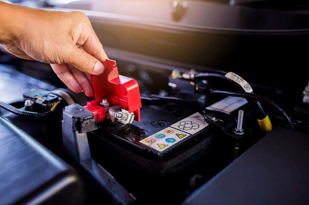 A mechanic testing a car battery, one of the MINI Cooper parts that you may need to replace