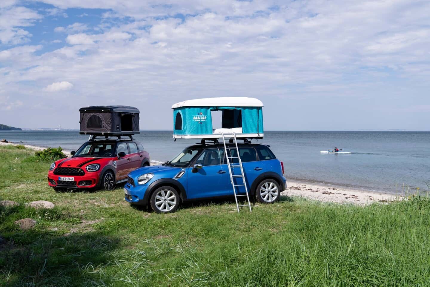 Two used MINI vehicles parked by a coast with campers on their roofs