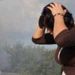 Frustrated woman looking at smoking car engine