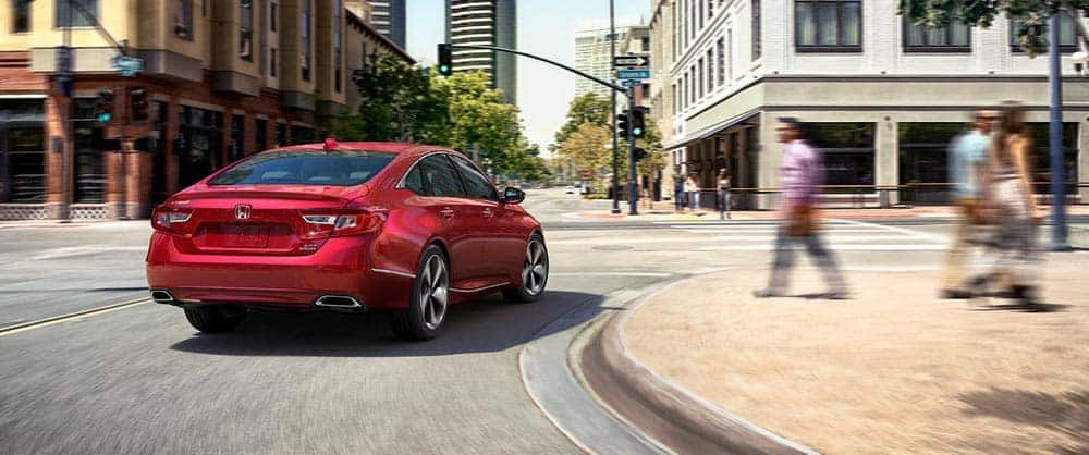 A red Honda Accord driving through the city A red Honda Accord driving around a corner on a city street