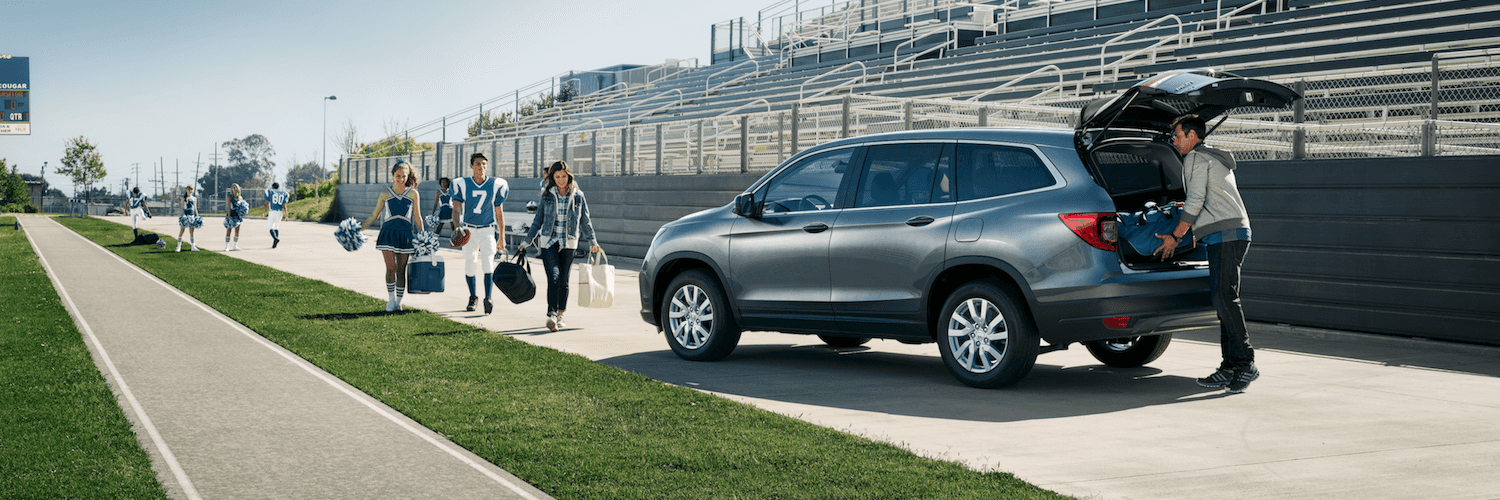 Honda Pilot at a Highschool Football Game A family walking to their Honda Pilot after a highschool football game.