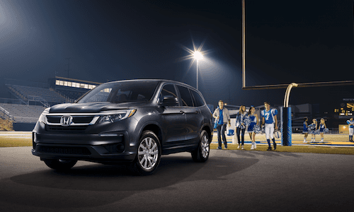 A family walking back to their Honda Pilot at night A family at a highschool footbal game walking to their 2019 Honda Pilot
