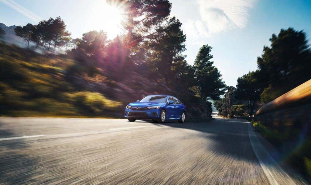 2023 Honda Civic Sedan LX driving down a road