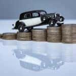 Car driving up stacks of coins, symbolizing the Honda finance process