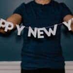 Person holding a garland that spells "HAPPY NEW YEAR"