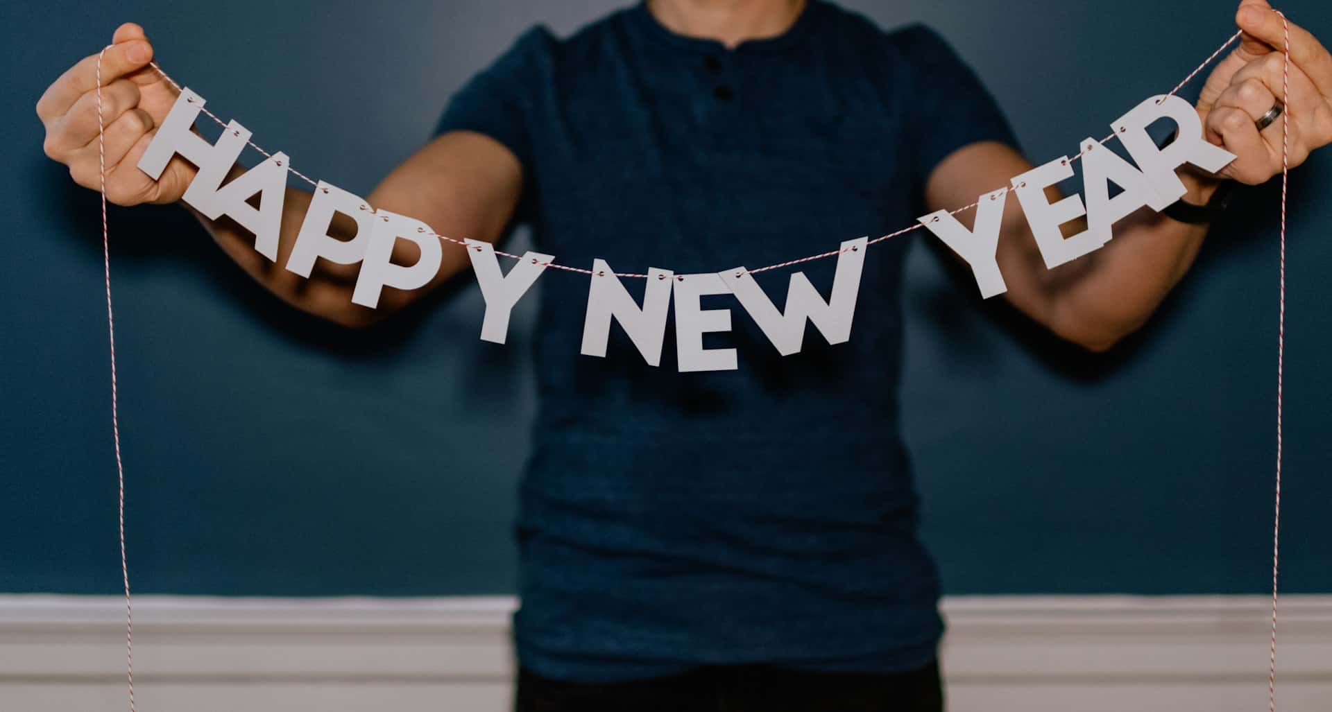 Person holding a garland that spells "HAPPY NEW YEAR"
