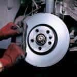 A service technician working on a brake rotor on a luxury vehicle.