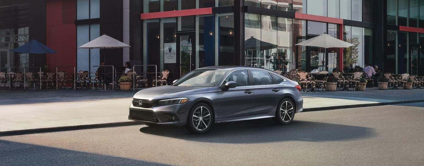 A grey 2024 Honda Civic is shown parked on the side of a city street.