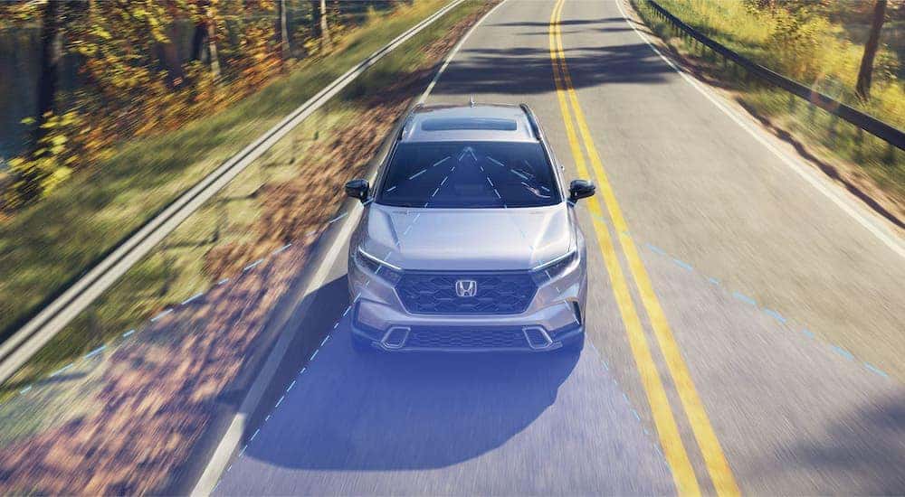 A grey 2024 Honda CR-V Hybrid Sport Touring Hybrid is shown from the front with simulated safety lines.