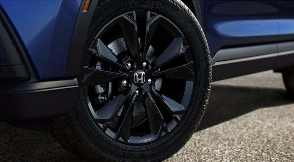 A close up of the wheel on a blue 2024 Honda CR-V Sport Touring is shown at a Honda dealer.