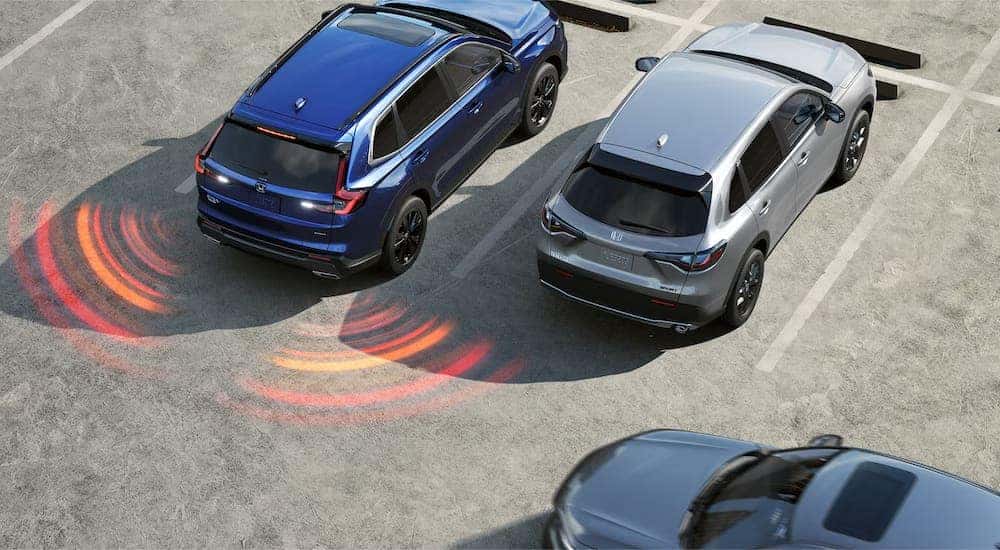 A blue 2024 Honda CR-V Sport Touring Hybrid is shown backing up in a parking lot.