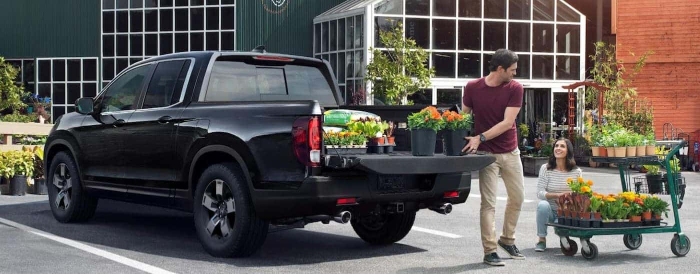 A black 2025 Honda Ridgeline RTL is shown parked near a greenery.