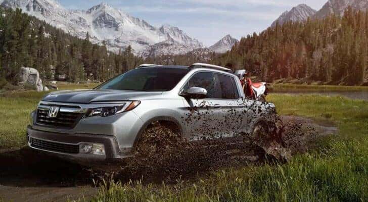 A silver 2020 Honda Ridgeline RTL-E is shown driving off-road.