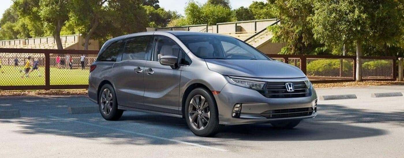 A silver 2024 Honda Odyssey is shown parked near a Honda dealer in Knoxville.
