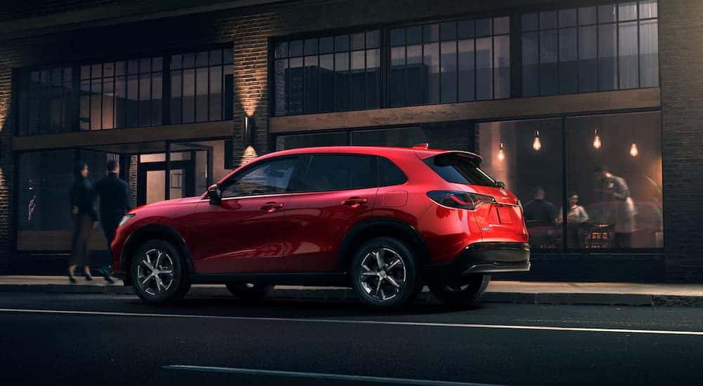 Rear view of a red 2025 Honda HR-V parked by a curb after visiting a Honda dealer in Knoxville.