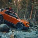 An orange 2025 Honda Passport Trailsport Elite driving through a river.