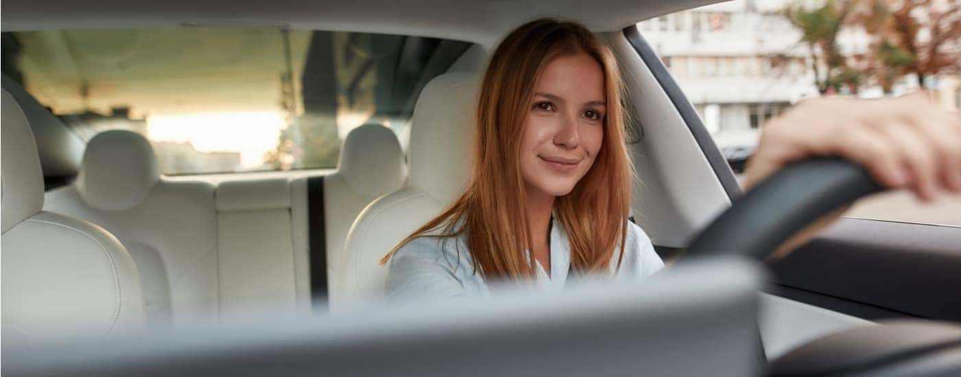 A woman is driving her car to a dealer to sell her car.