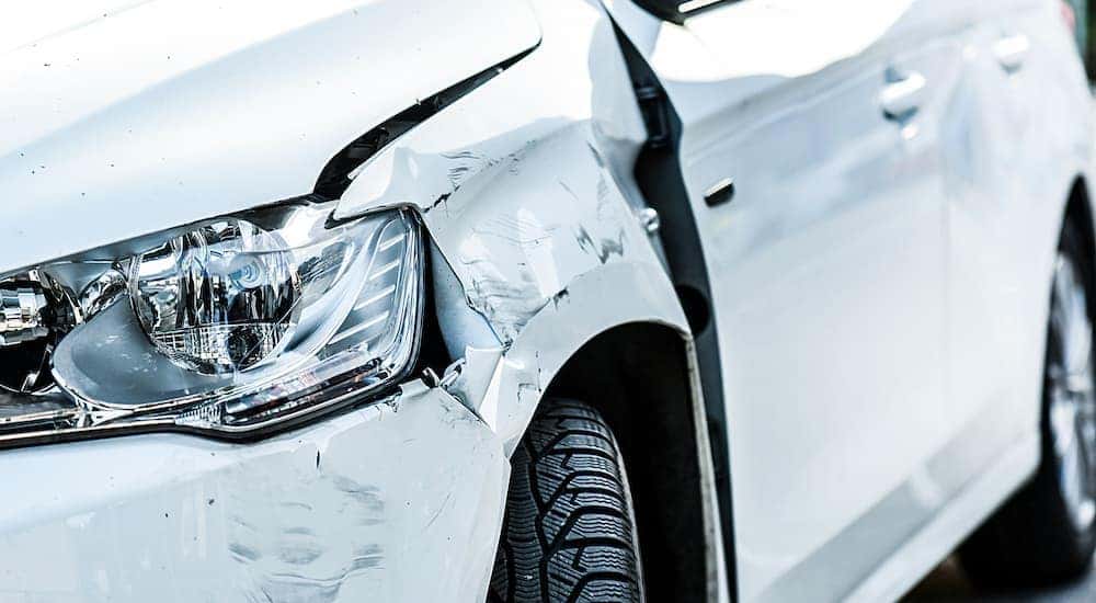 A white car is shown with some damage to the front end.