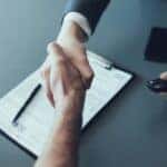A handshake is shown over paperwork after a customer searched how to "sell my car".