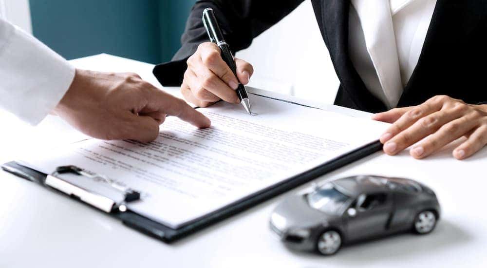 A customer is shown signing paperwork at a dealership.