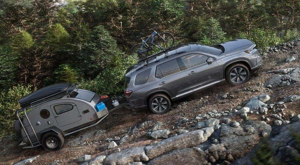 A grey 2025 Honda Pilot for sale from the side while off-road.