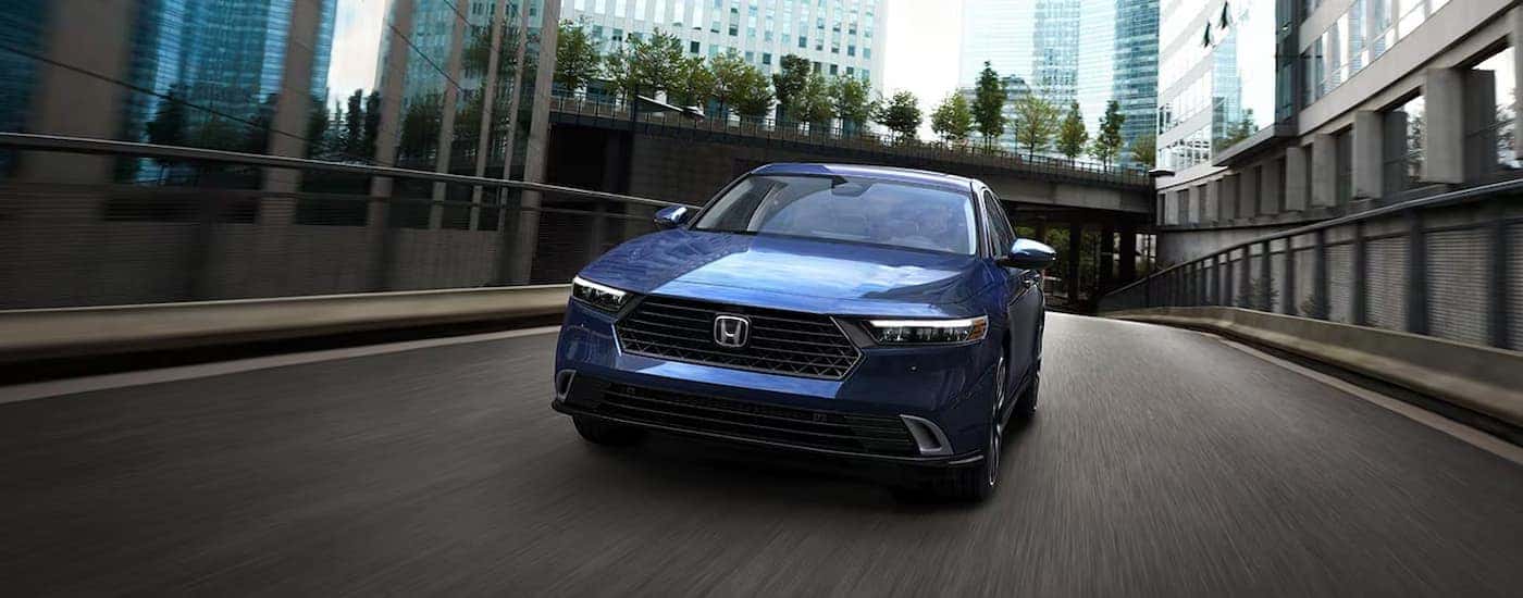A blue 2025 Honda Accord for sale driving down a city street
