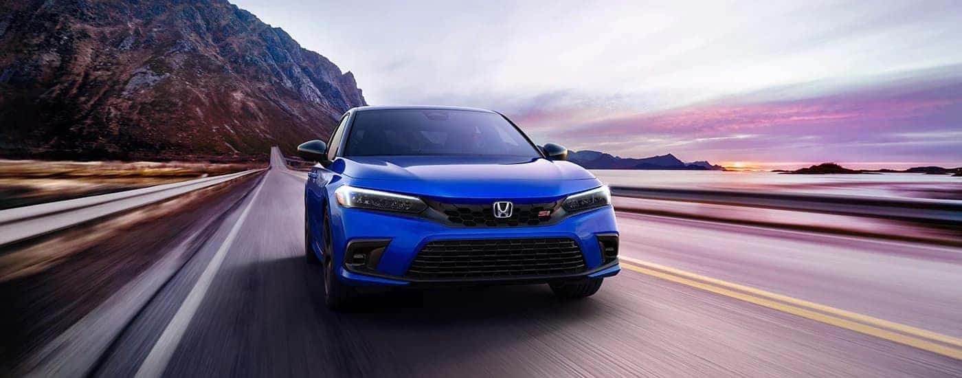 A blue 2023 Honda Civic Si driving down a highway