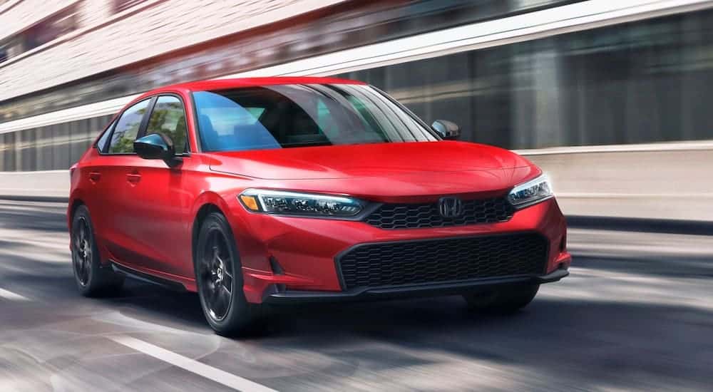 Red 2026 Honda Civic Sport for sale in Knoxville driving down a road.
