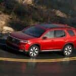 A red 2025 Honda Pilot driving on a highway