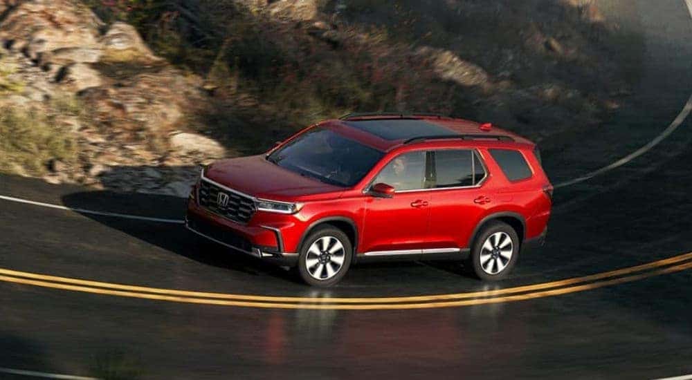 A red 2025 Honda Pilot driving on a highway