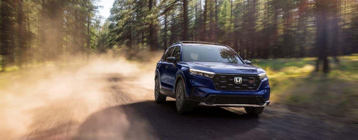 Blue 2026 Honda CR-V Trailsport driving on a dusty dirt road