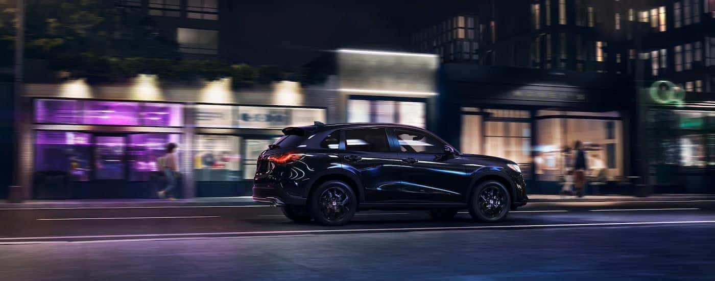 Side view of a black 2025 Honda HR-V Sport driving on a city street