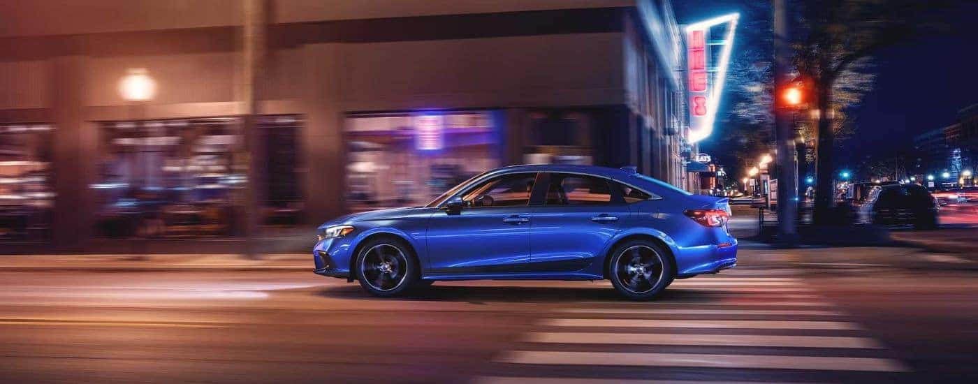 A blue 2024 Honda Civic is shown driving on a city street after visiting a Honda dealer near Morristown.
