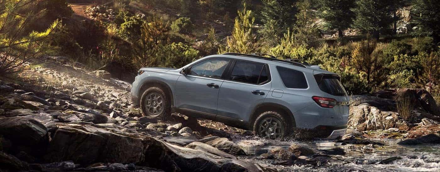 A gray used 2023 Honda Pilot TrailSport off-roading on rocks