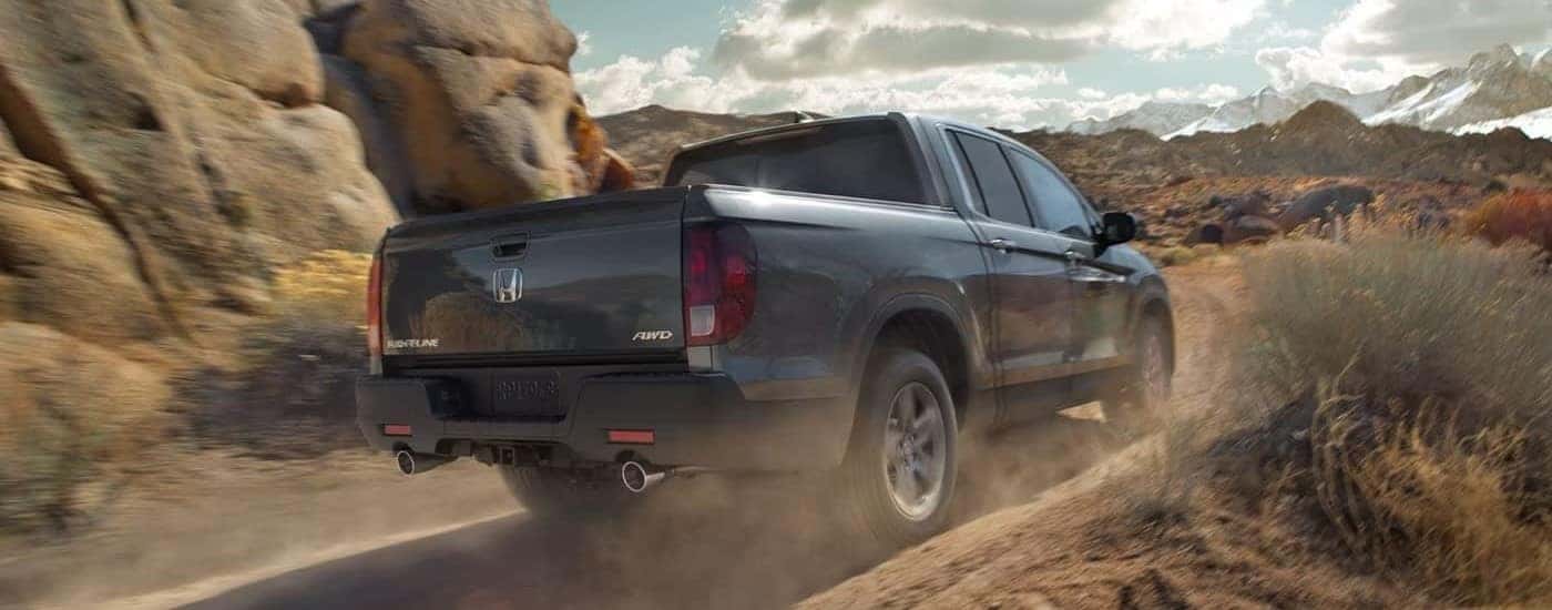 A gray used 2023 Honda Ridgeline RTL-E off-roading on a dirt trail