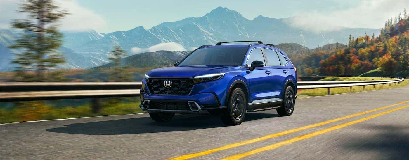 Blue 2023 Honda CR-V Hybrid driving on a mountain road