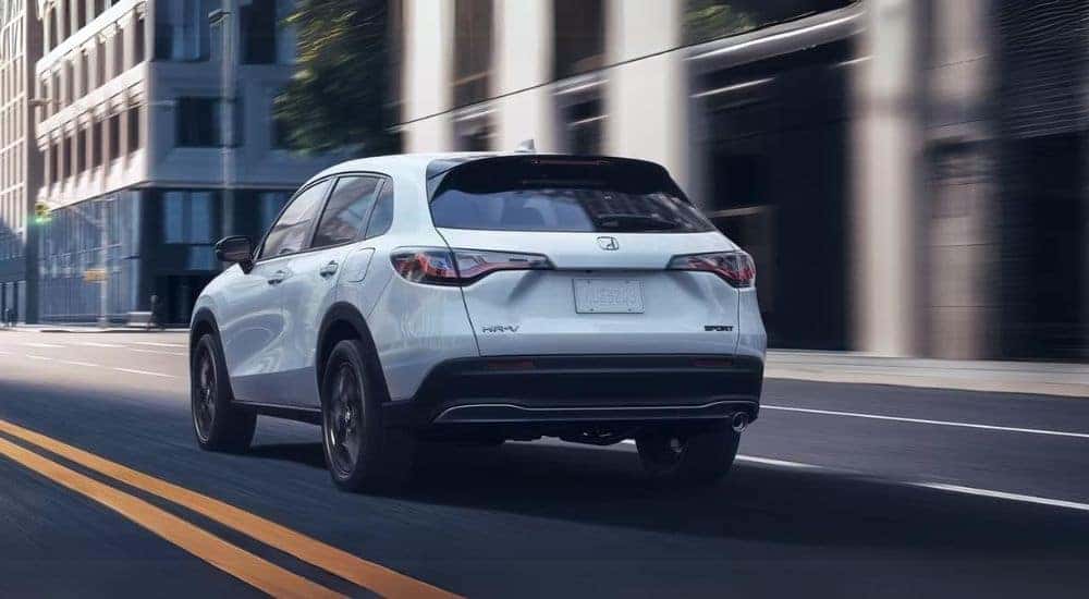 A white 2025 Honda HR-V Sport driving in a city