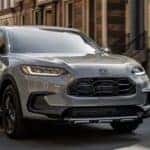 A gray 2025 Honda HR-V Sport driving for sale in a city