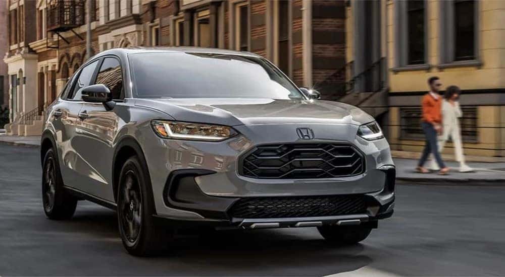 A gray 2025 Honda HR-V Sport driving for sale in a city