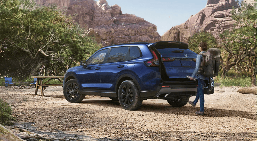 A person opening the trunk of their blue 2026 Honda CR-V