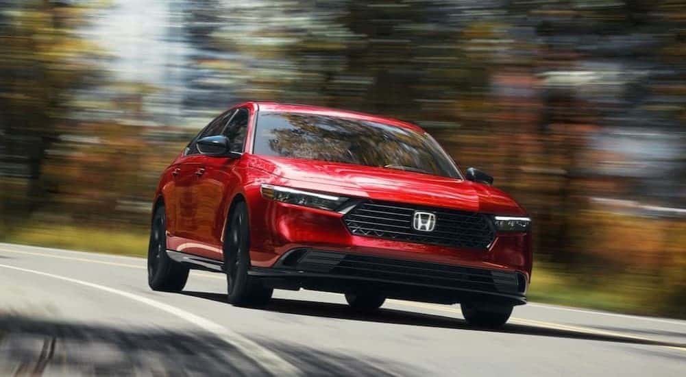 A red 2026 Honda Accord Sport-L Hybrid driving on a highway.