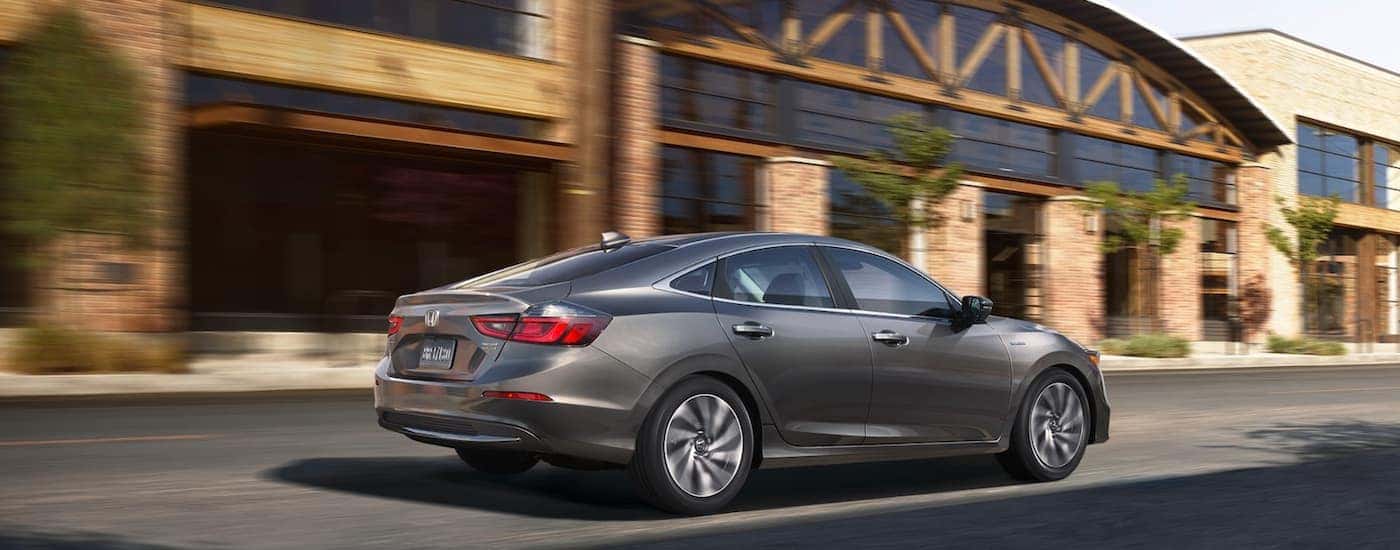 Grey 2021 Honda Insight Touring driving by a building.