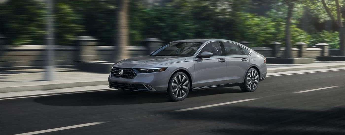 Silver 2023 Honda Accord Touring Hybrid driving through a city