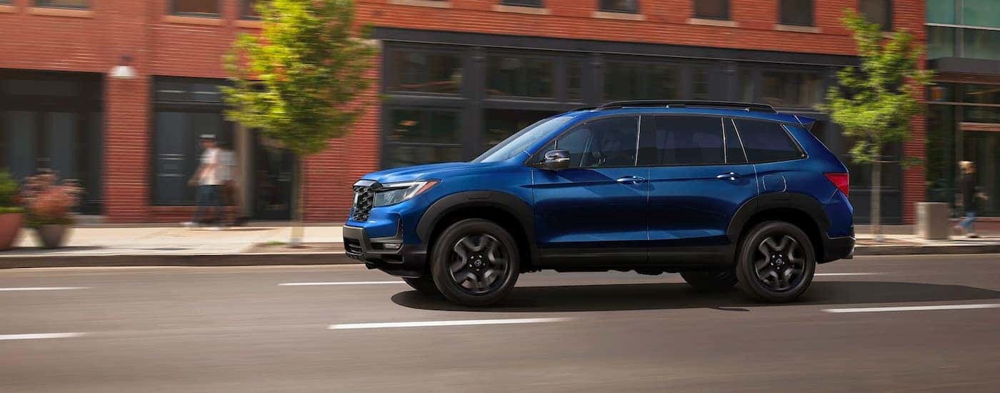Blue 2023 Honda Passport Elite driving through a town