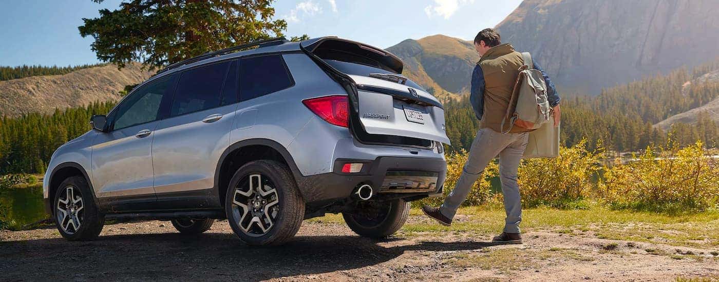 A person opening the trunk of a silver 2023 Honda Passport Elite