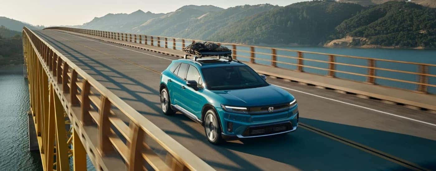 Teal 2024 Honda Prologue Elite driving by water.
